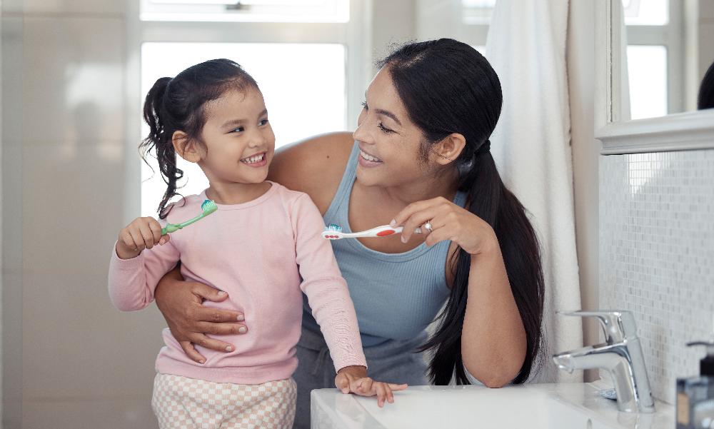 a mom and her daughter holding toothbrush